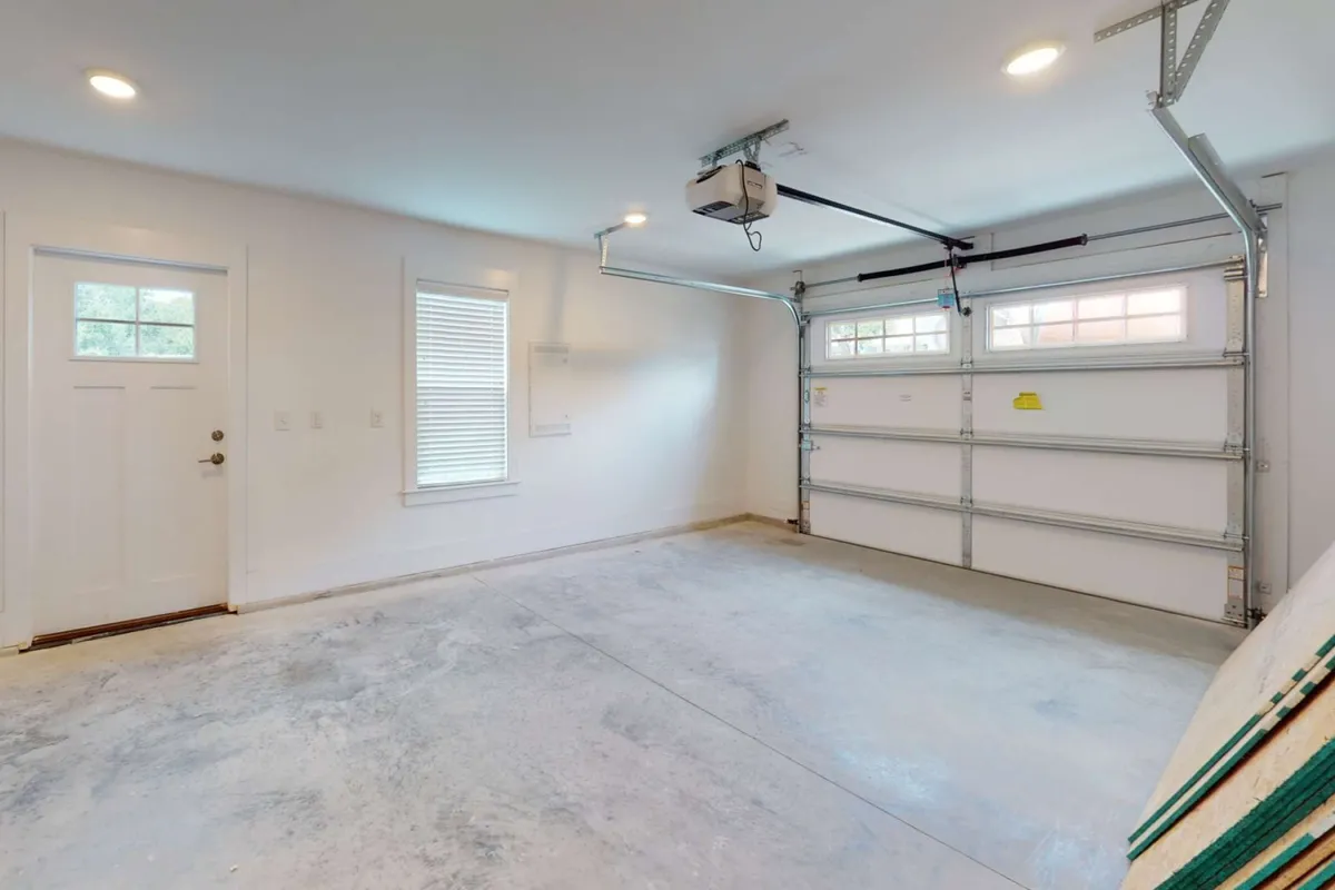 A view focused on the garage door and entry door, with windows providing natural light. The image emphasizes a well-organized, practical space ideal for parking, storing beach gear, or preparing for outings.