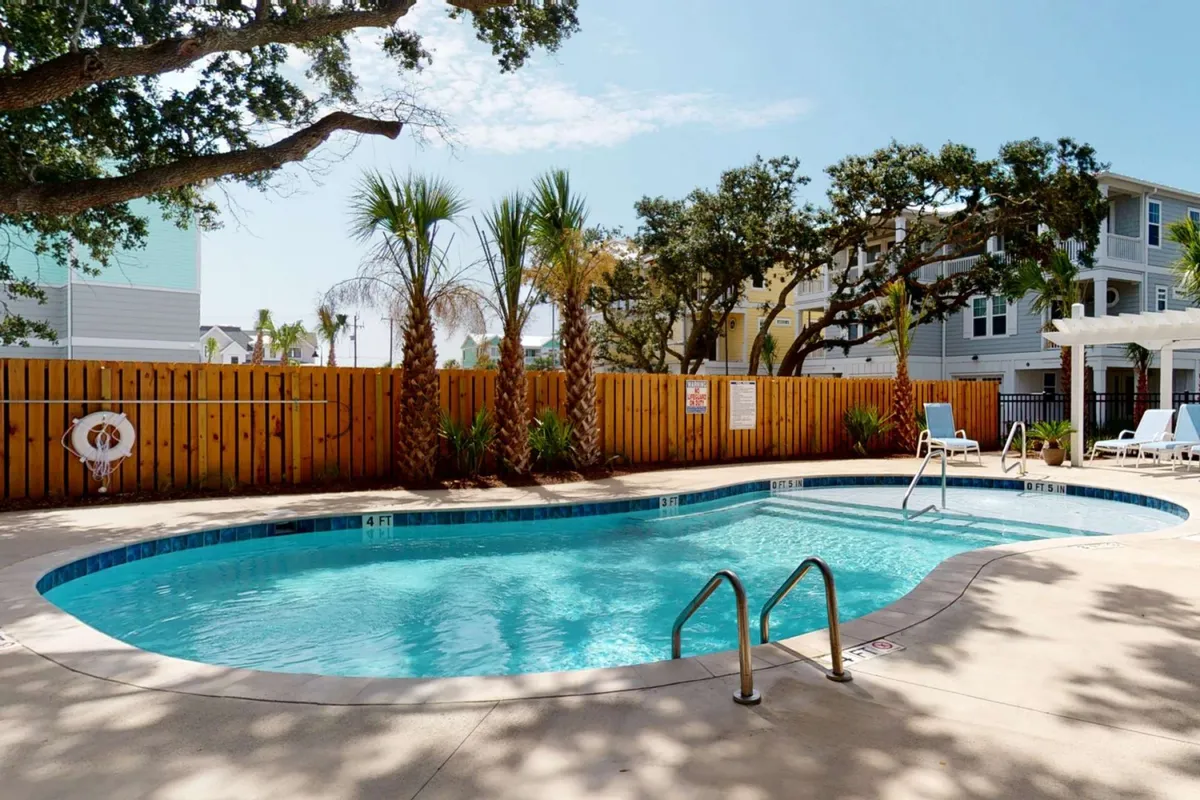 A sparkling swimming pool framed by palm trees and lush greenery. Wide pool steps offer easy access, and the tranquil atmosphere invites both relaxation and social gatherings. The area is clean and well-maintained, suggesting modern amenities and a family-friendly environment.